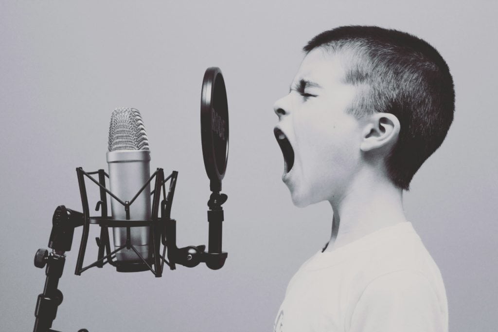 young boy standing infront of microphne yelling