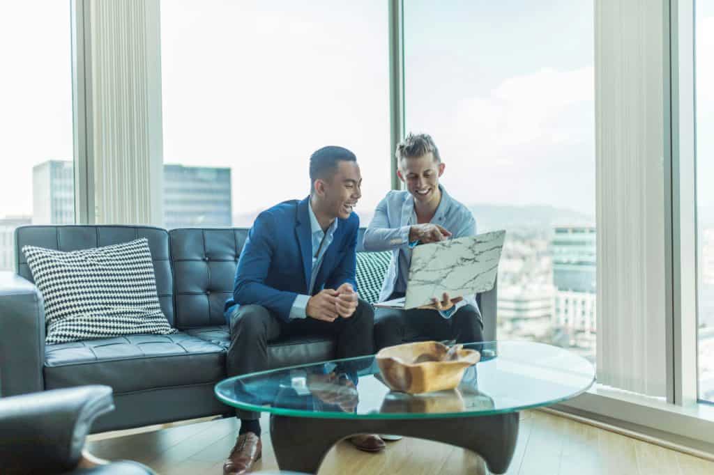 Two young men looking at laptop in front of window