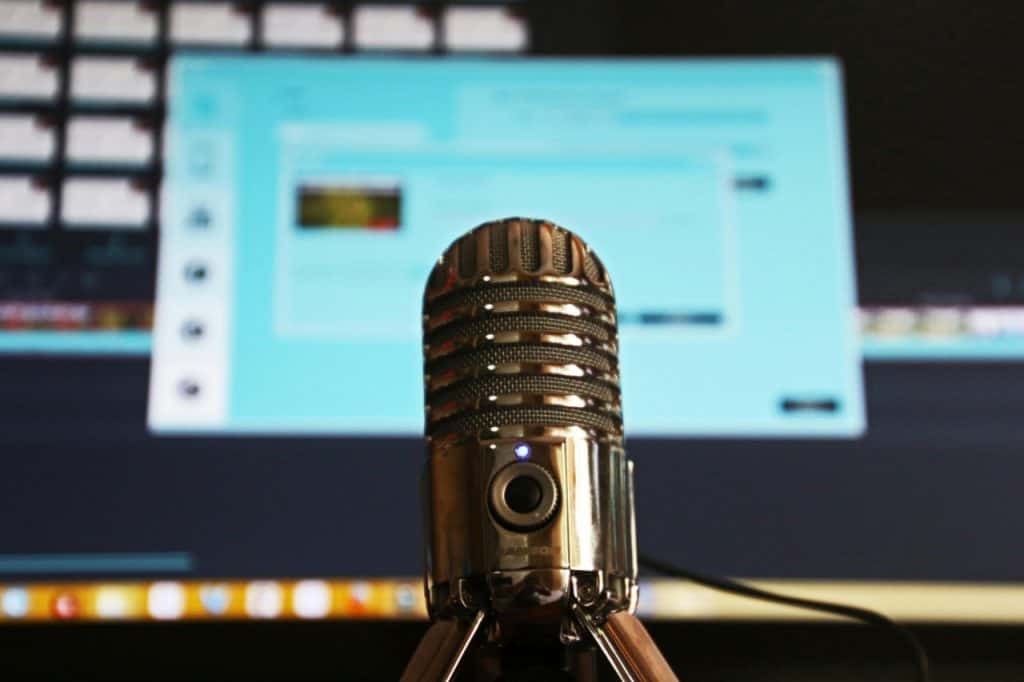 Old vintage microphone on stand infront of computer monitor